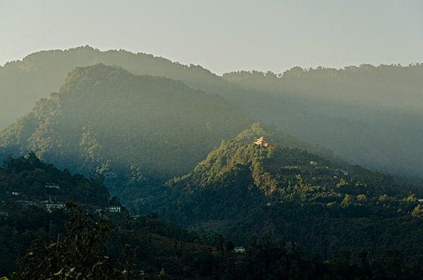 The setting sun casts a beam of light on a monastery, East Sikkim