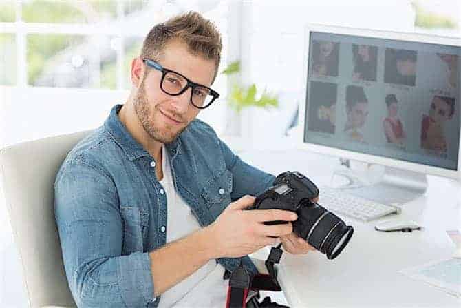 Handsome photographer holding his camera smiling at camera in creative office Best-Mid-Range-DSLR-Zoom-LENS-DX