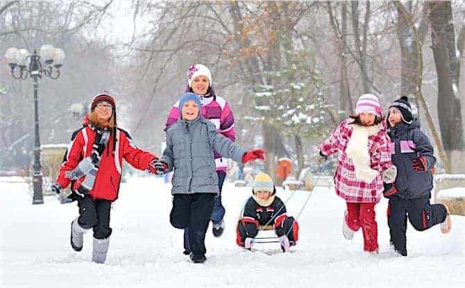 Group of children and mother playing on snow in winter time How to Take Better Vacation Photos