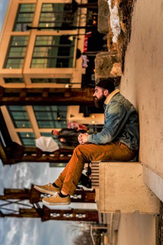 Forced perspective photography of a man sitting on the sidewalk