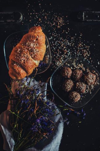 Croissant on black background with another dish next to it.