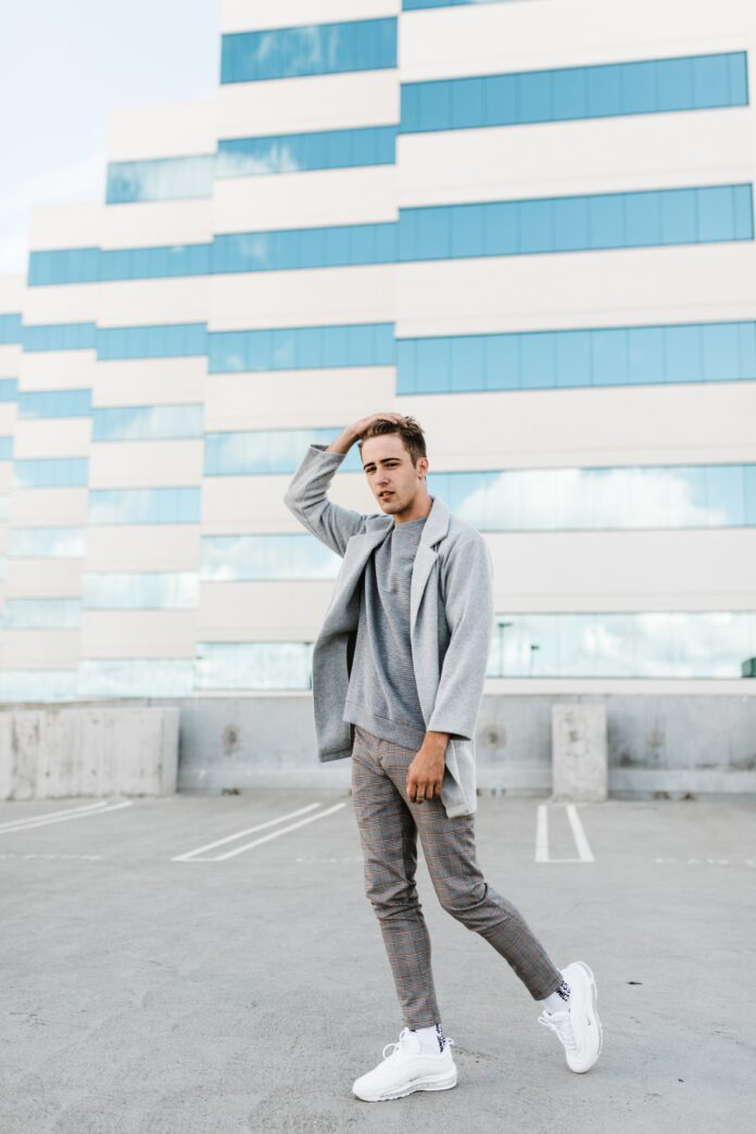 Young man posing on a rooftop parking garage with one hand on top of his head.