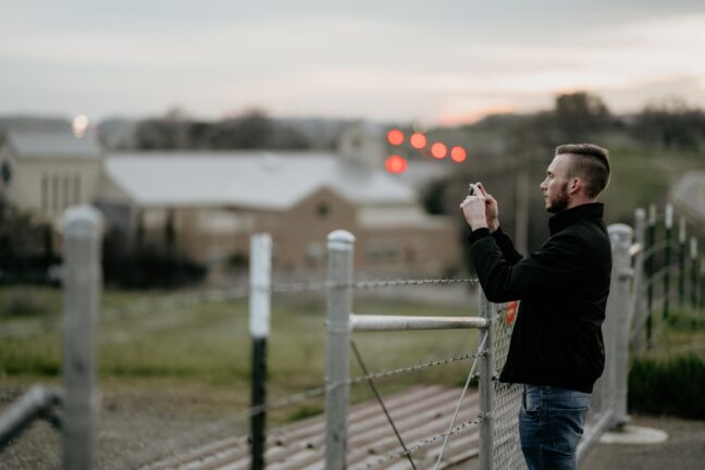 man doing smartphone photography by a fence best iPhone tele lens
