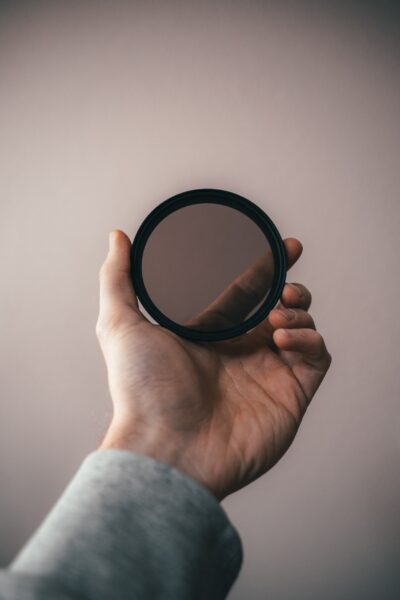 Hand holding up a filter in front of a white wall