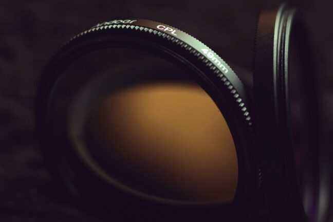 Close-up of a circular polarizer in a dark environment with a second filter in the background