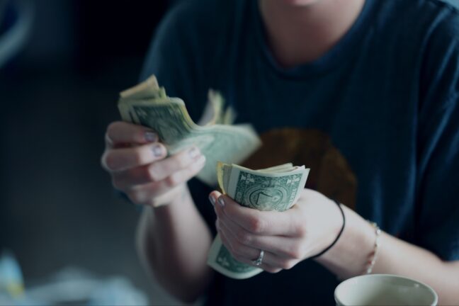 Close-up of woman's hands as she counts dollar bills