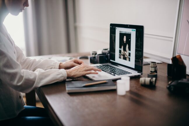 Business woman in white blouse sitting at desk looking at photos on a laptop