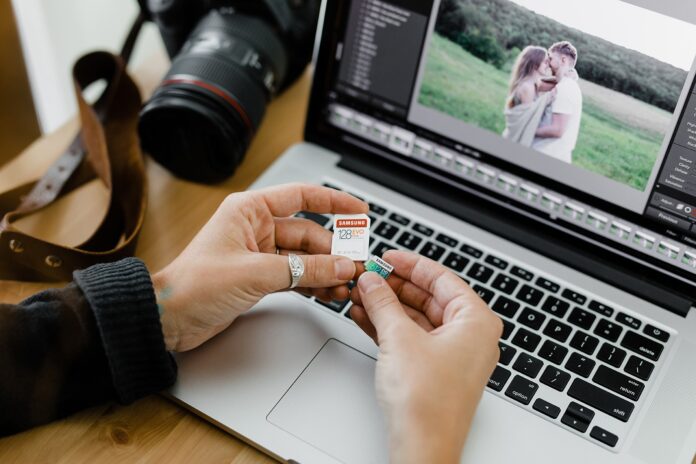 Person holding an SD and microSD card, comparing them for laptop use.