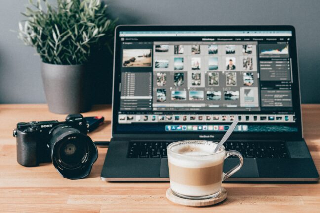 Coffee cup in front of a Sony camera and Macbook Pro laptop with Lightroom Classic open.