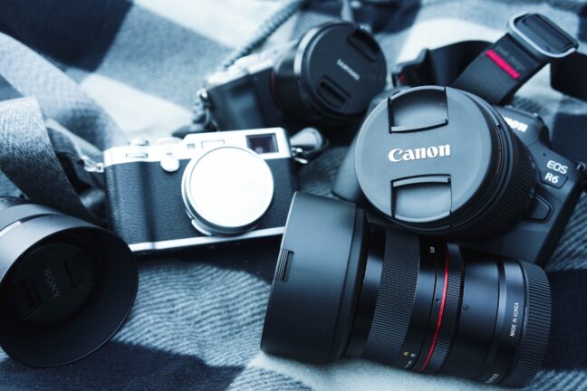 Canon, Fujifilm, Sony, and Samyang cameras and lenses arranged haphazardly on a checkered blanket.