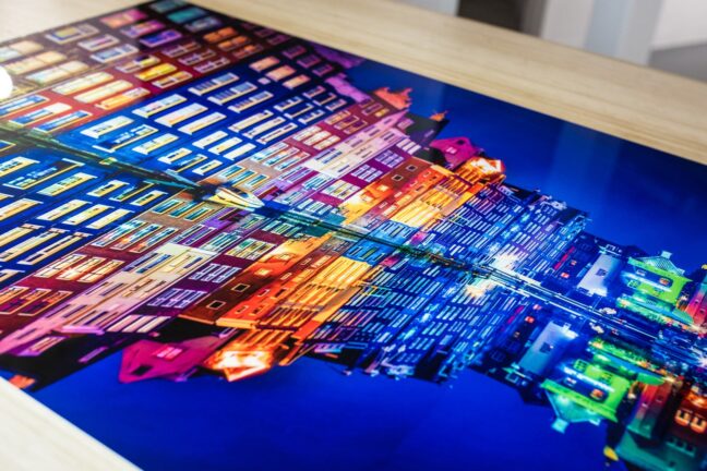 A metal print on a table featuring colorful houses along a canal at night.