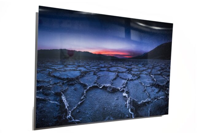 Metal print on a white wall featuring salt flats at sunset.