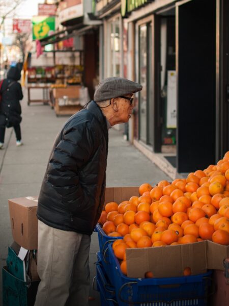 Man looking at oranges on the street.