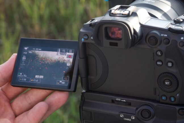 Black Canon EOS R5 with a battery grip and a flip screen popped outward.