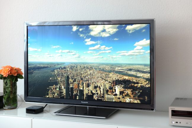 TV displaying an expansive cityscape under a beautiful blue sky with white clouds.