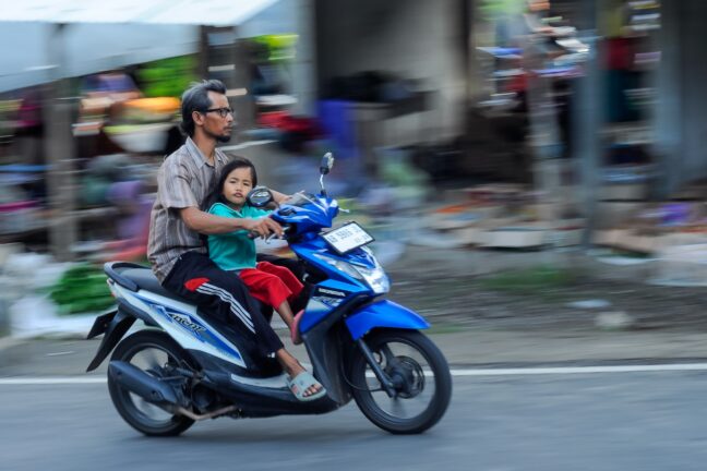 blurred panning photography, motorcyclist using a Honda Beat automatic motorbike, selective focus.