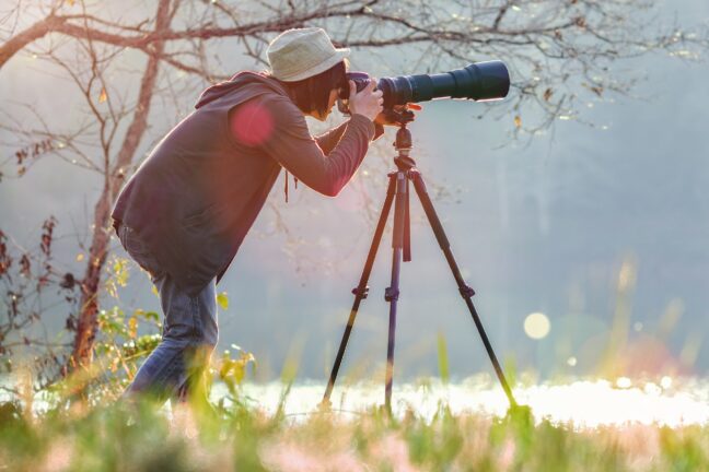 photographer taking photo with long telephoto on a tripod