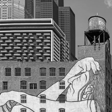 Street art in downtown Chicago of a person sitting leaned back with their hand on their head and eyes closed across the wall of a big building.