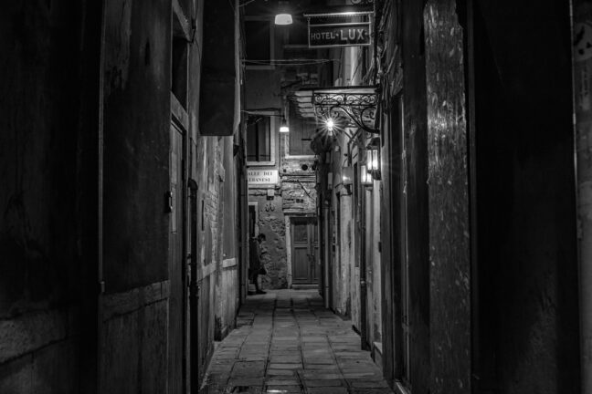 Venice alleyway outside the Hotel Lux with a woman passing in the distance.