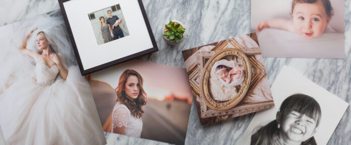 Assorted photo prints by Miller's Professional Imaging spread on a marble surface, including a bride in her wedding dress, a framed photo of a couple with a baby, a young woman's portrait, newborn twins in a vintage frame, a smiling baby, and a giggling child in black and white. A small succulent plant adds a touch of greenery.