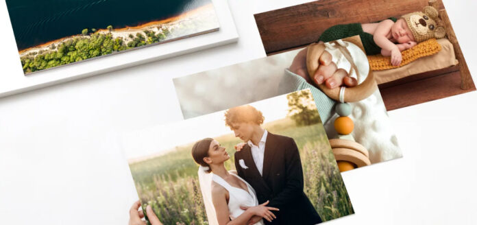 A collection of printed photographs by Saal Digital spread out on a surface, featuring a scenic beach photo on top, a couple dressed in wedding attire in the center, and a sleeping baby in the corner.